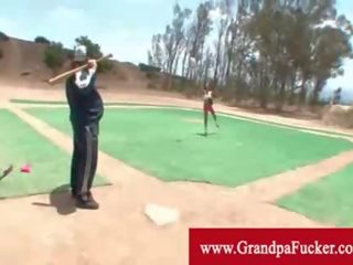 Old man showing a young lady how to swing